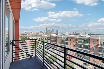 A balcony overlooks a cityscape with buildings and a cloudy sky.